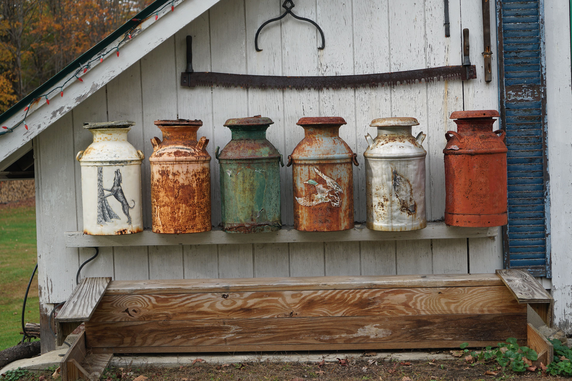 old metal jugs against the side of a white shed or barn
